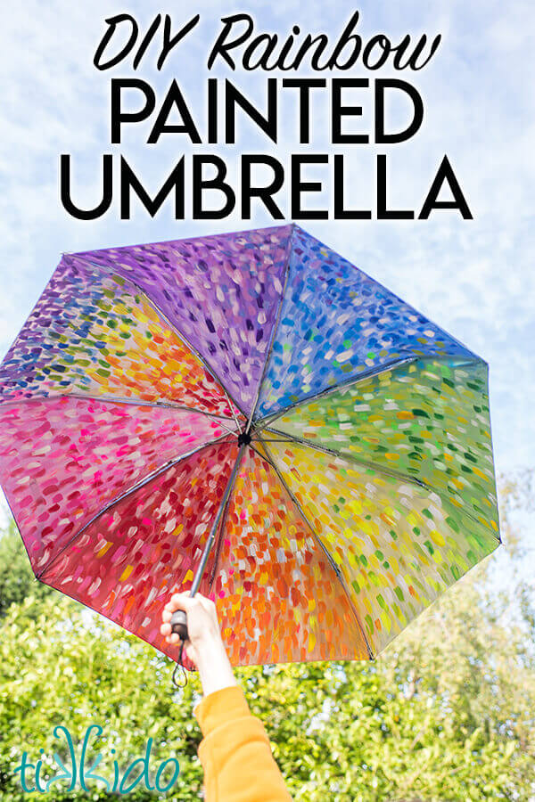 DIY painted umbrella painted in abstract rainbow colors with acrylic paint.