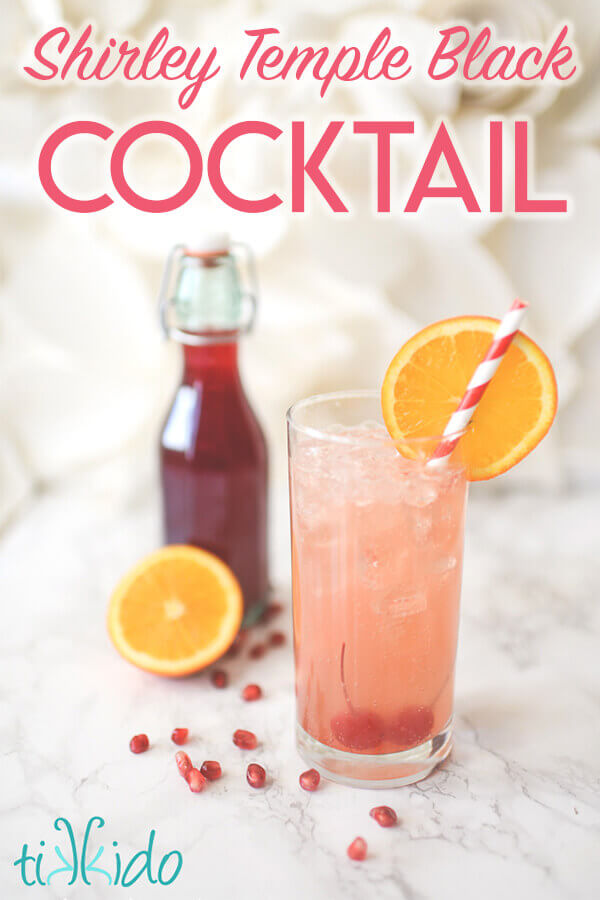 Shirley Temple Black Cocktail with a red and white straw in front of a bottle of homemade grenadine syrup.