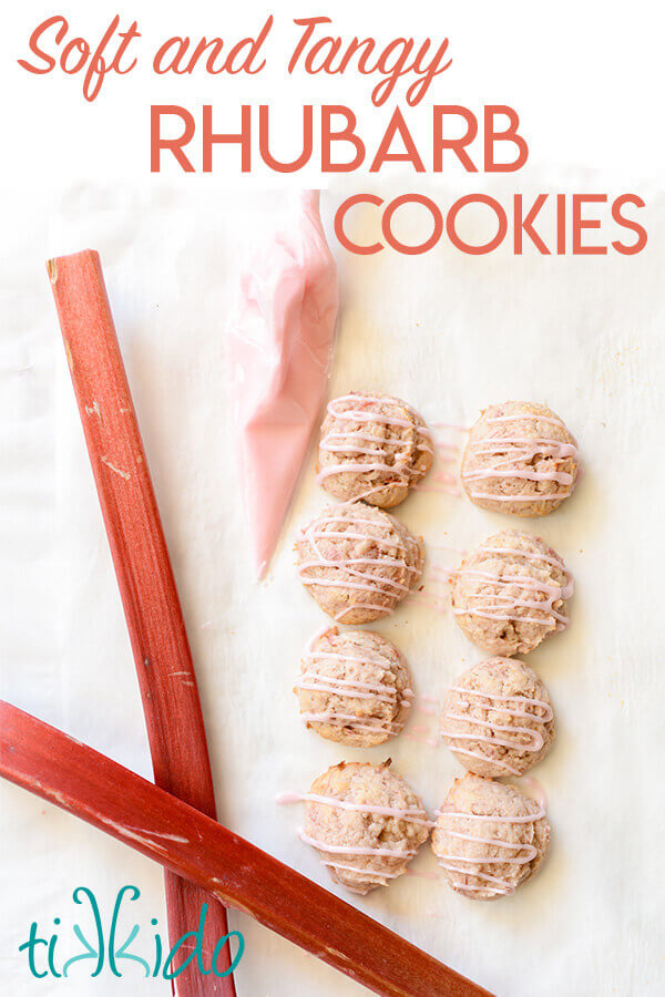 Rhubarb cookies next to two stalks of fresh rhubarb on a white marble surface.