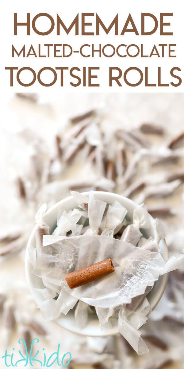 Homemade chocolate malt tootsie rolls wrapped in waxed paper, in a white dish, with one unwrapped tootsie roll sitting on top of the pile.