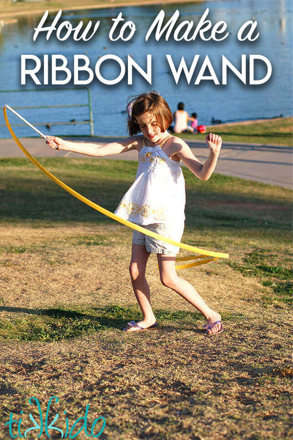 Little girl in a park playing with a DIY ribbon wand, with text overlay reading "How to Make a Ribbon Wand."