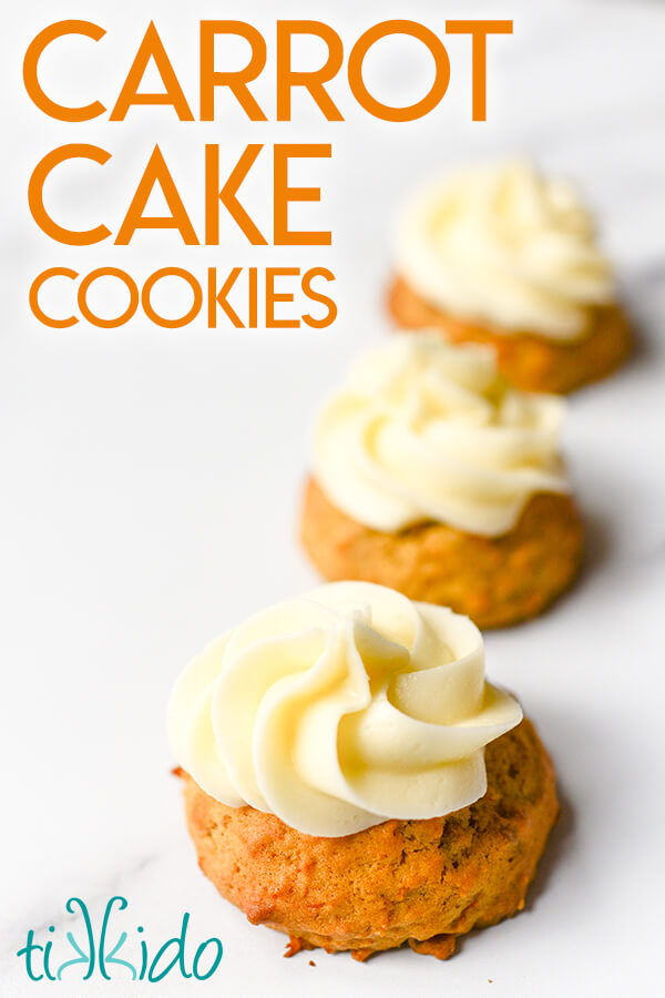 Carrot cake cookies topped with cream cheese icing on a white marble surface.