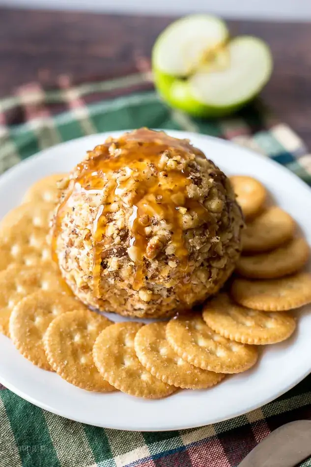 Caramel apple cheese ball appetizer surrounded by ritz crackers.
