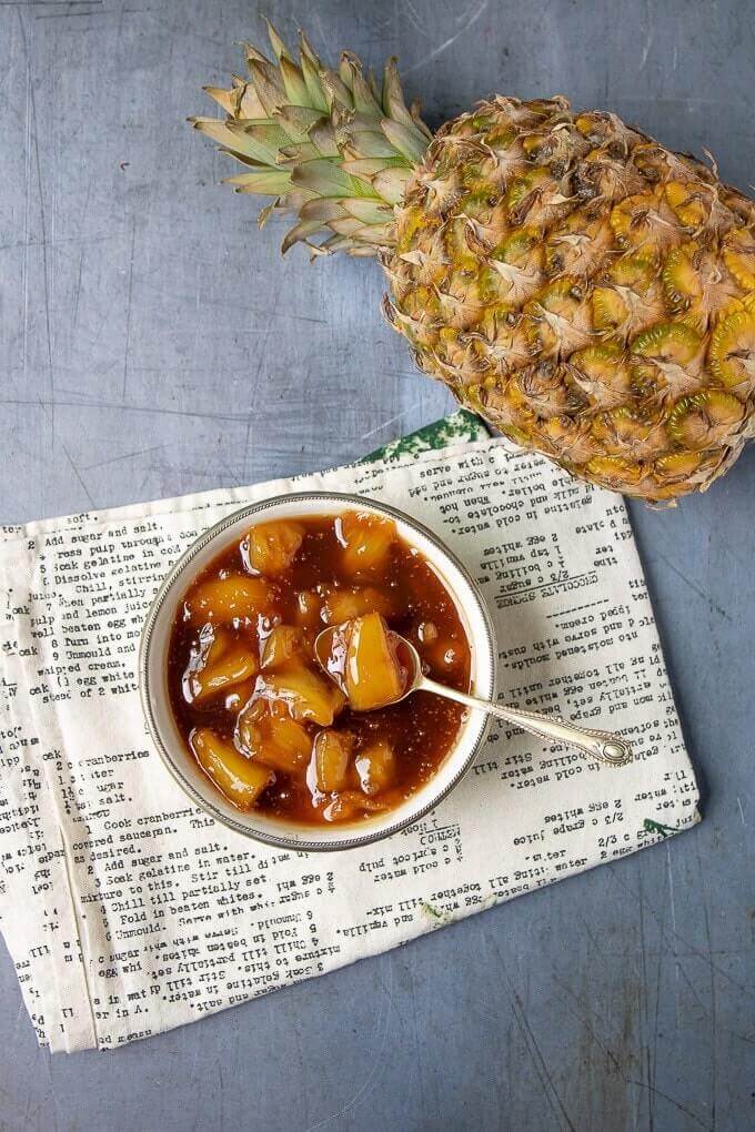 Vanilla pineapple compote Ice Cream Topping in a white bowl next to a fresh pineapple.