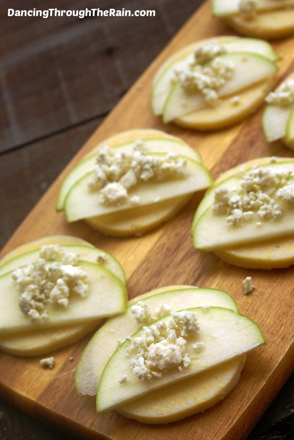 Polenta bites with apple and gorgonzola on a wooden serving tray.