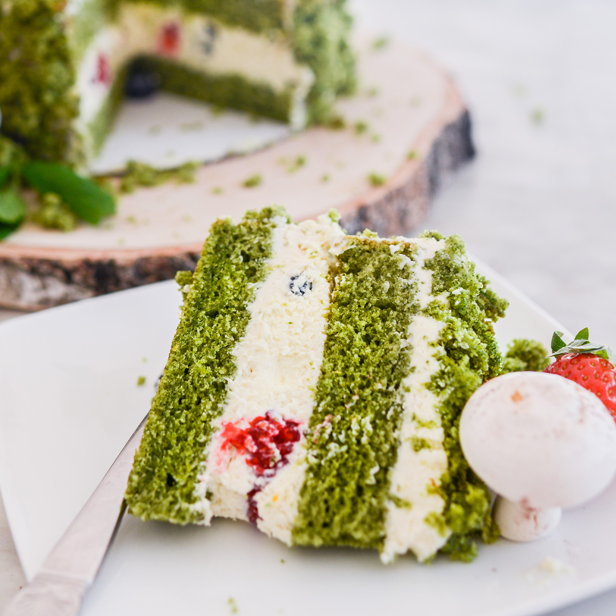 Slice of cake filled with Whipped Mascarpone Filling and fresh berries, sitting on a white plate with a fork.