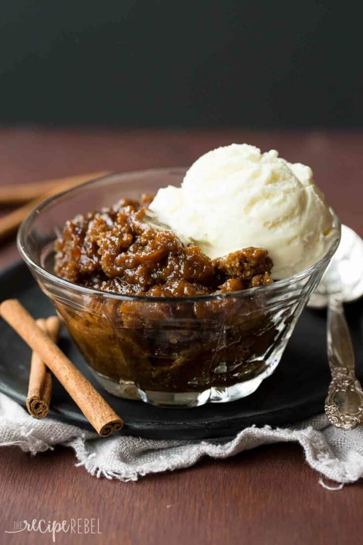 Slow cooker gingerbread pudding cake in a glass bowl topped with a scoop of vanilla ice cream.