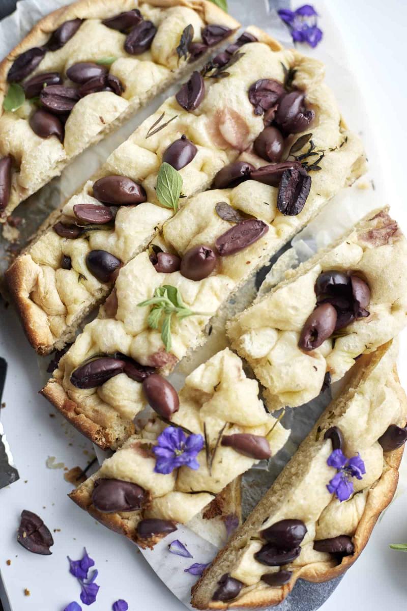 Focaccia bread made in a slow cooker, topped with black olives and fresh herbs.