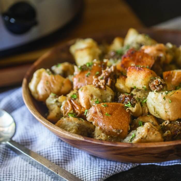 Slow cooker sausage stuffing in a wooden bowl.