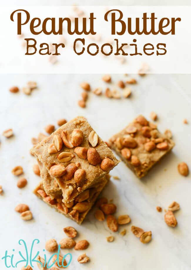 Peanut butter bar cookies on a white marble background surrounded by peanuts.