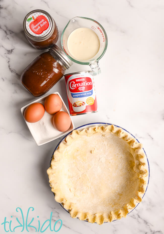 Ingredients for Apple butter pie recipe arranged on a white marble surface.