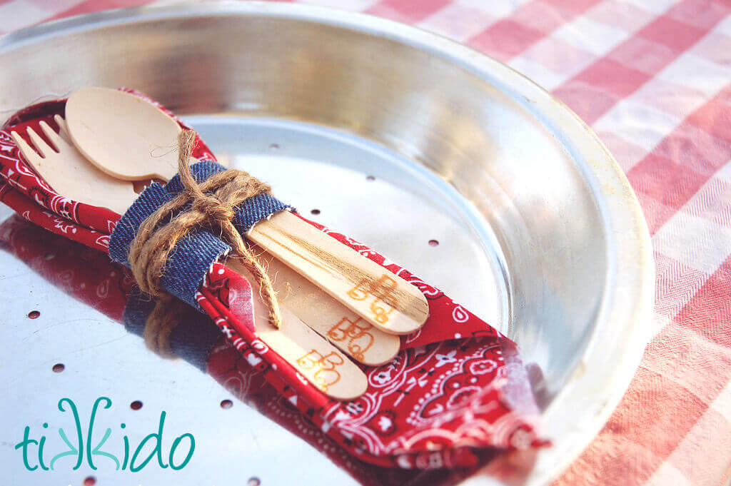 Pie tin plate, bandana napkin, and wooden silverware branded with BBQ tied with a denim and string napkin ring.