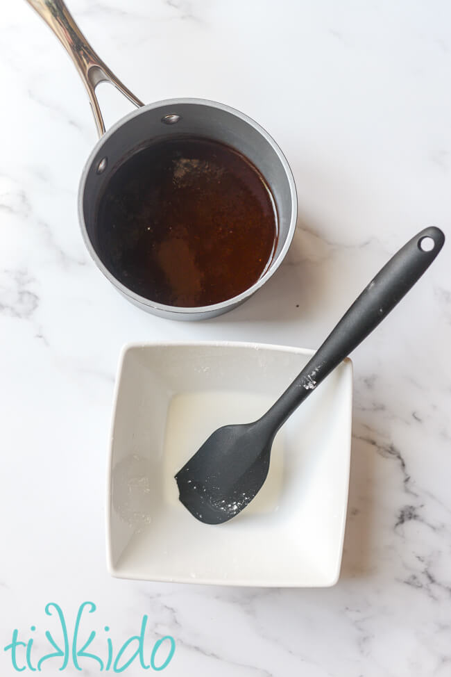 Pan of Cherry BBQ Sauce and bowl with cornstarch and water to thicken the cherry barbecue sauce, on a white marble surface.