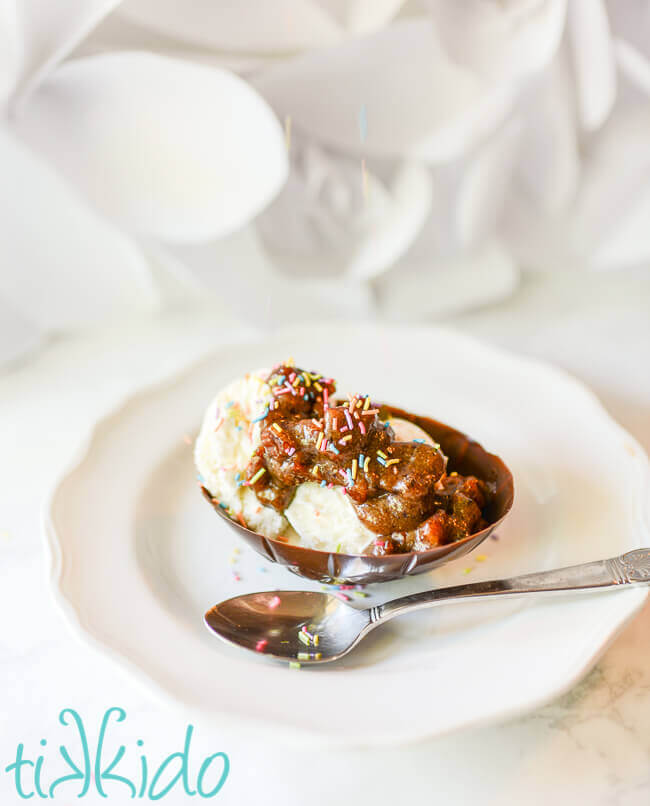 Edible chocolate Easter egg ice cream bowl filled with vanilla icing, praline sauce, and rainbow sprinkles.