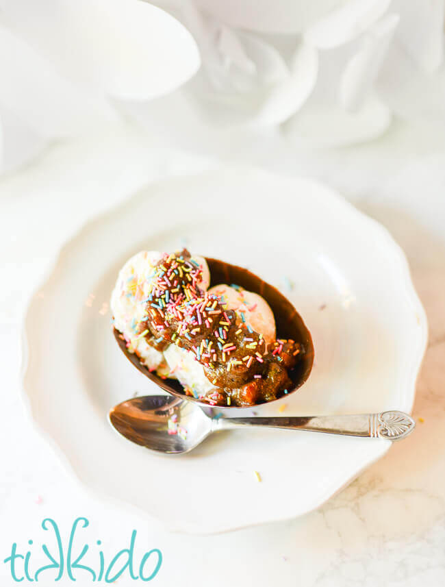 Edible chocolate Easter egg ice cream bowl filled with vanilla icing, praline sauce, and rainbow sprinkles.