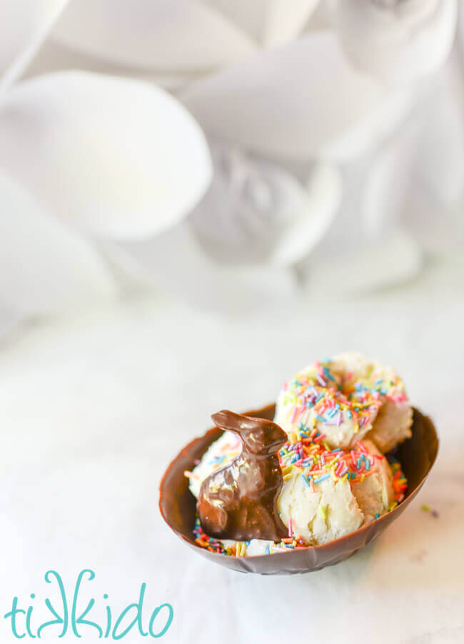 Chocolate Easter Egg Edible Ice Cream Bowl filled with vanilla ice cream, pastel rainbow sprinkles, and a small chocolate bunny, on a white background