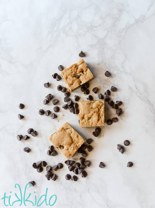 Chocolate chip bar cookies surrounded by chocolate chips on a white marble background.