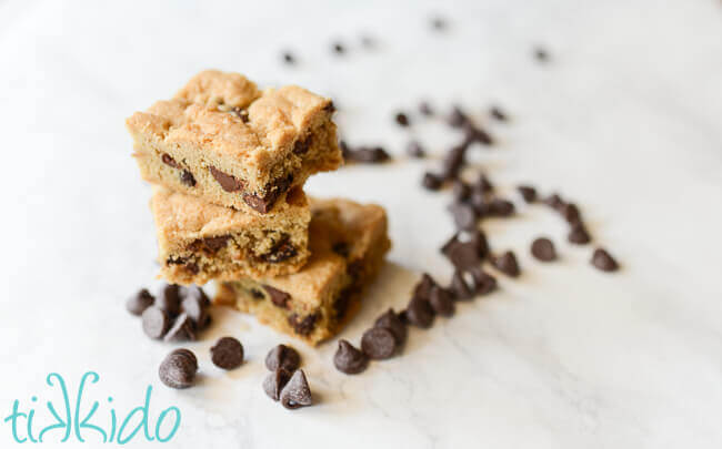 Chocolate chip bar cookies surrounded by chocolate chips on a white marble background.