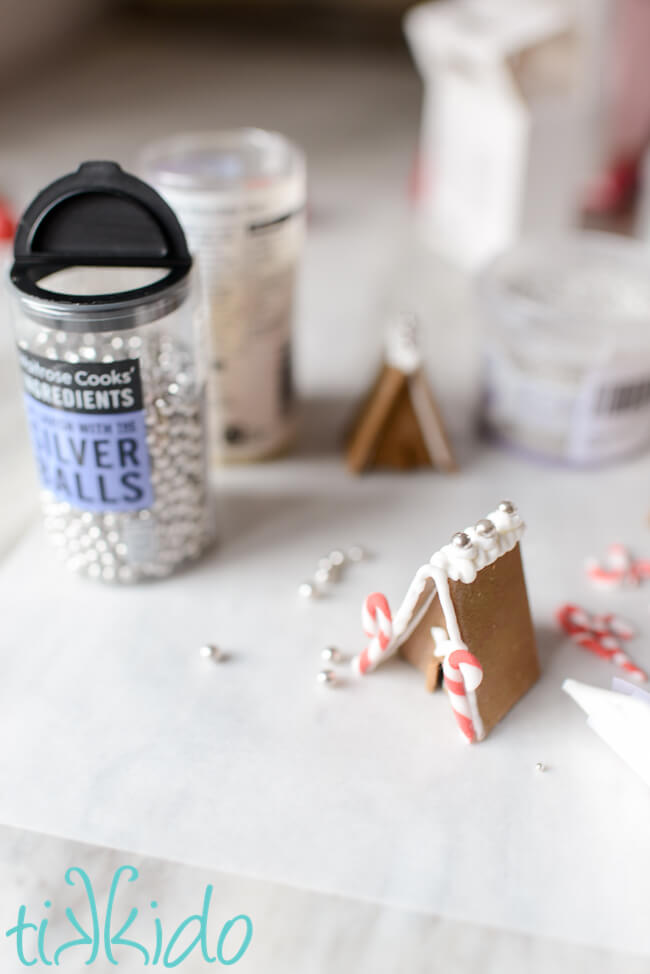 Miniature Gingerbread House Cupcake Toppers being decorated with sprinkles.