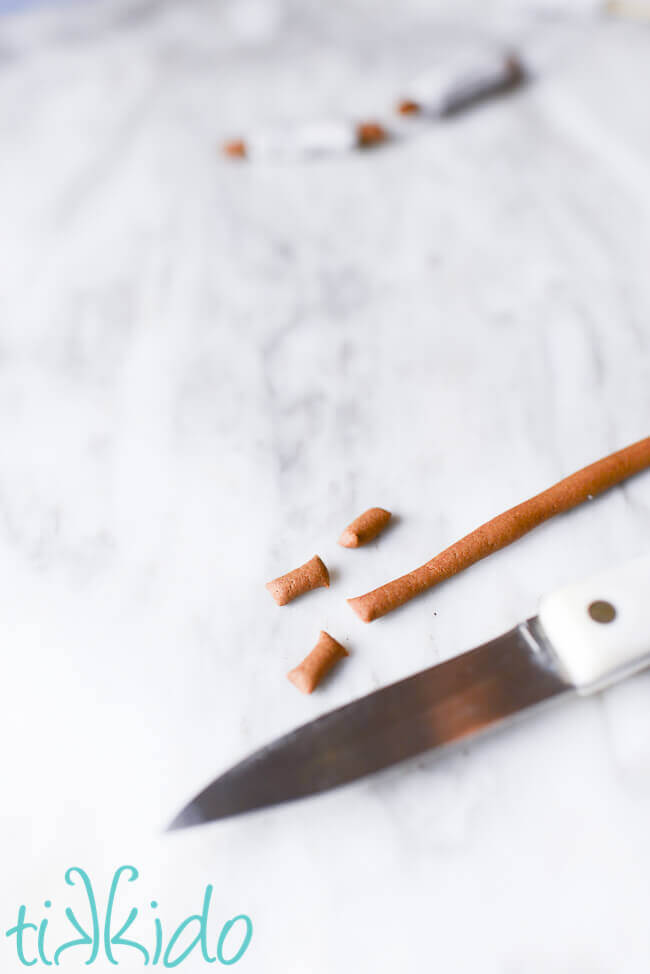 Brown gum paste being cut with a paring knife to make Christmas Baking Cupcake Toppers