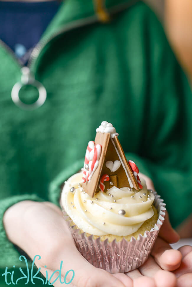 Christmas cupcake topped with a miniature A-Frame gingerbread house made from gum paste.