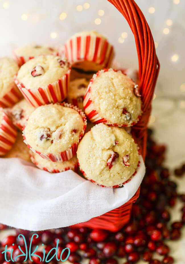 Basket full of cranberry muffins, surrounded by fresh cranberries.