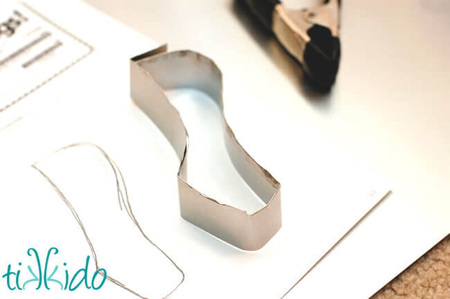 DIY cookie cutter being bent into shape based on a sketch of a ballet shoe.