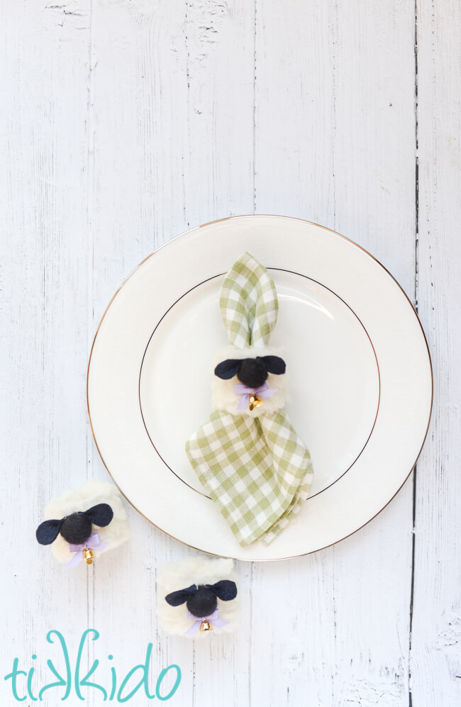 Easter Sheep Napkin Rings, one holding a napkin on a plate, two next to the plate.