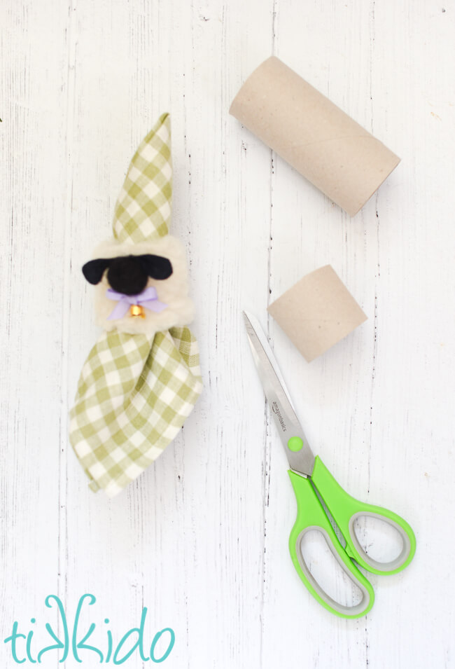 Cardboard toilet paper tubes being cut to make Easter napkin rings that look like sheep.