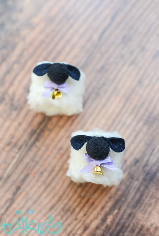 Two Easter Sheep Napkin Rings on a dark wooden surface.