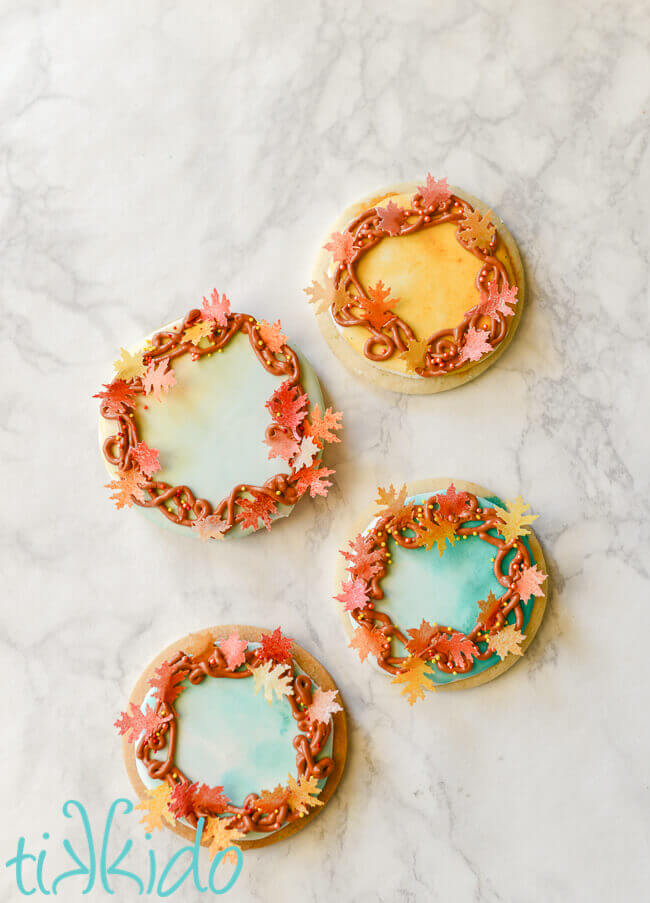 Four fall wreath sugar cookies on a white marble surface.