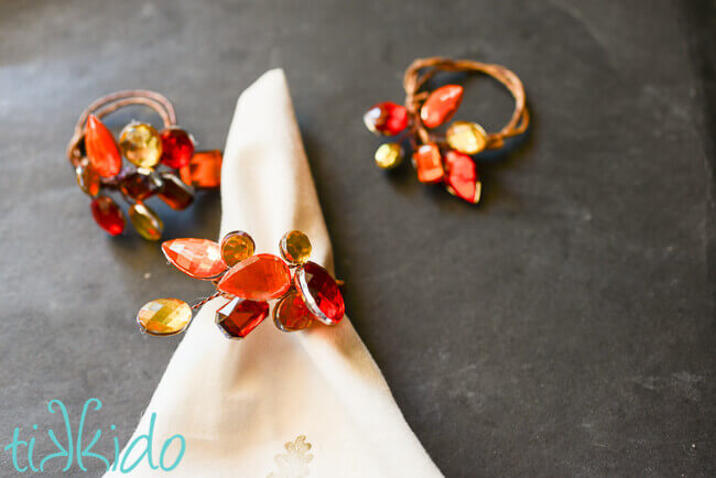 DIY napkin rings made with grapevine wire and large rhinestones in fall colors for Thanksgiving.