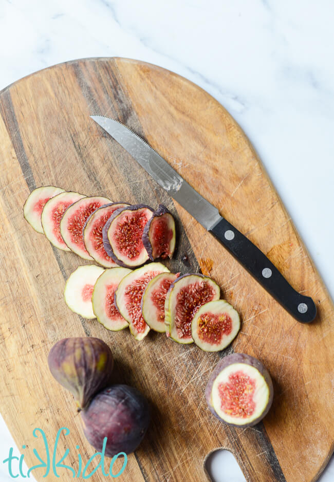 Sliced fresh figs on a wooden cutting board.