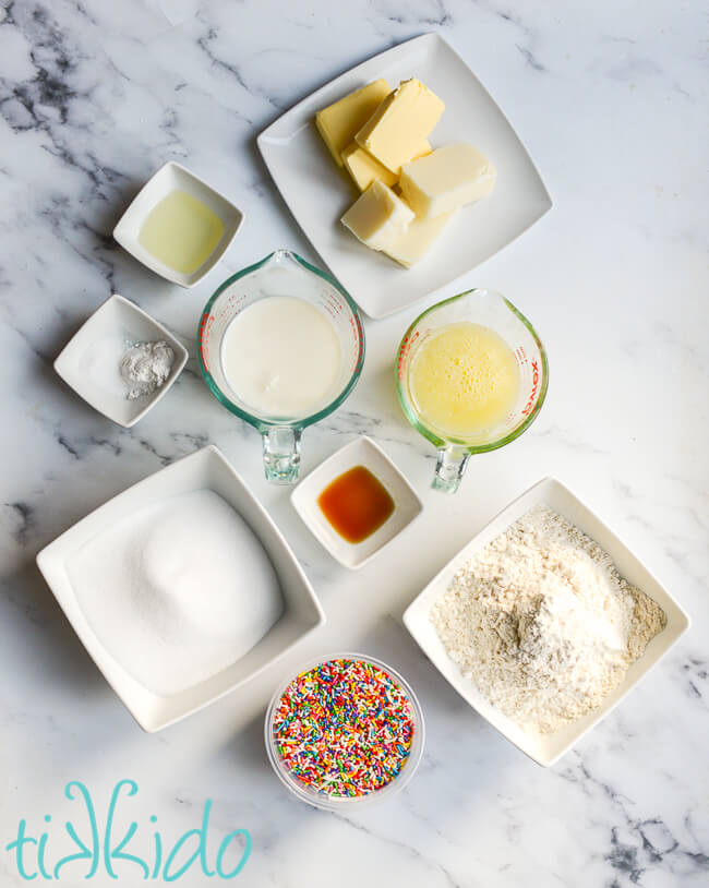 Funfetti cake ingredients on a white marble surface.