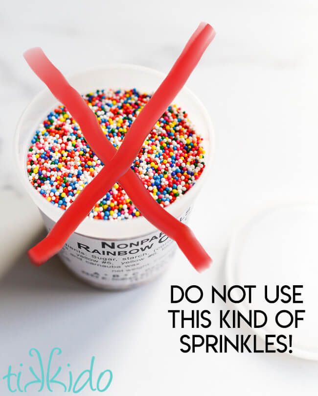 Container of rainbow nonpareils with a red X drawn on top and text overlay reading "Do not use this kind of sprinkles!" in a funfetti cake recipe.