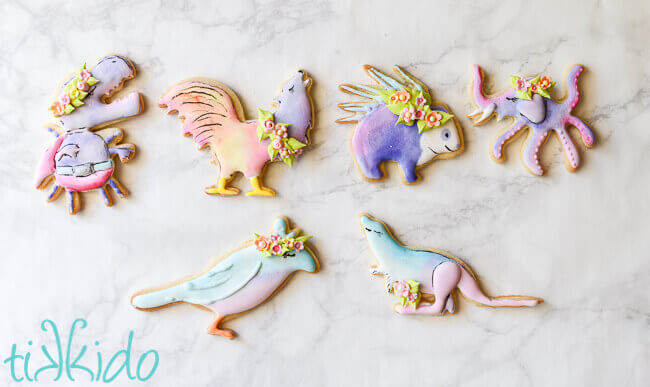GISHWHES mascot sugar cookies in pastel watercolor colors for Easter, with royal icing flower crowns, on a white background.
