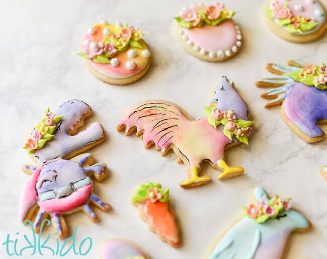 GISHWHES mascot sugar cookies in pastel watercolor colors for Easter, with royal icing flower crowns, on a white background.