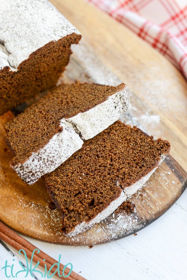 Gingerbread quick bread sliced on a wooden cutting board.