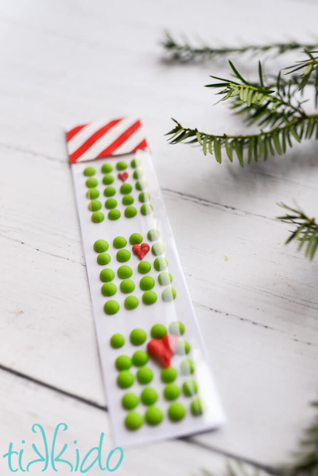 Grinch candy buttons packaged and on a white wooden surface.