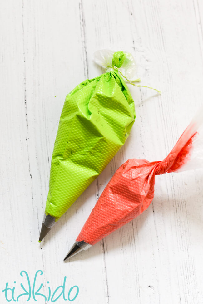 Green and red royal icing for making Grinch Candy Buttons in disposable piping bags.