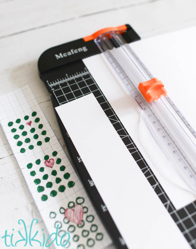 White cardstock being cut into strips for the Grinch Candy Buttons packaging.