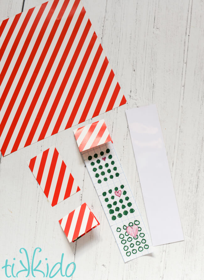 Red and white striped scrapbook paper being cut to size for the packaging for the Grinch Candy Buttons.