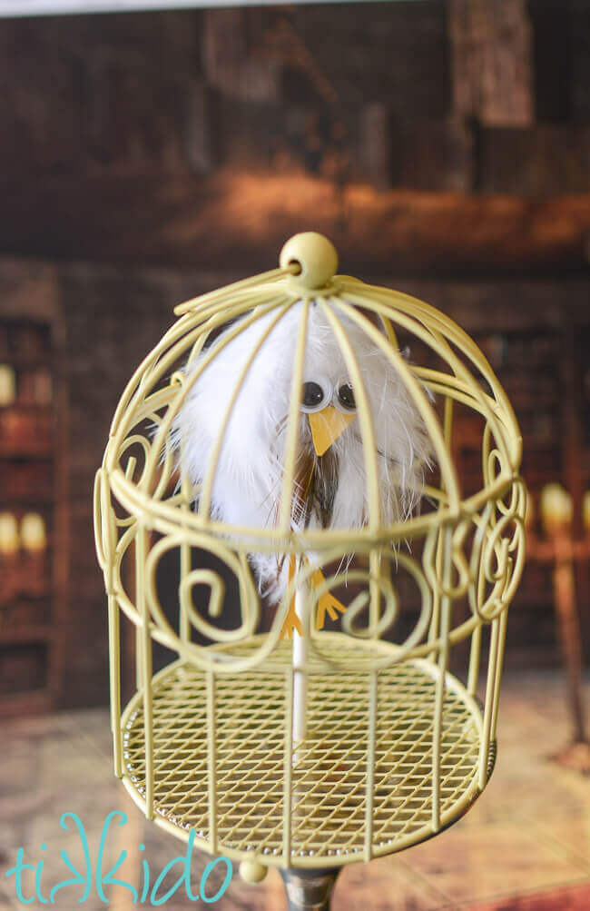 Lollipop that looks like a feather covered owl in a small yellow cage for a Harry Potter party.