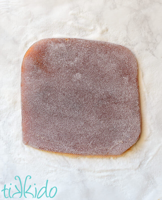 Peach jellies ready to be cut into shapes on a white marble surface.