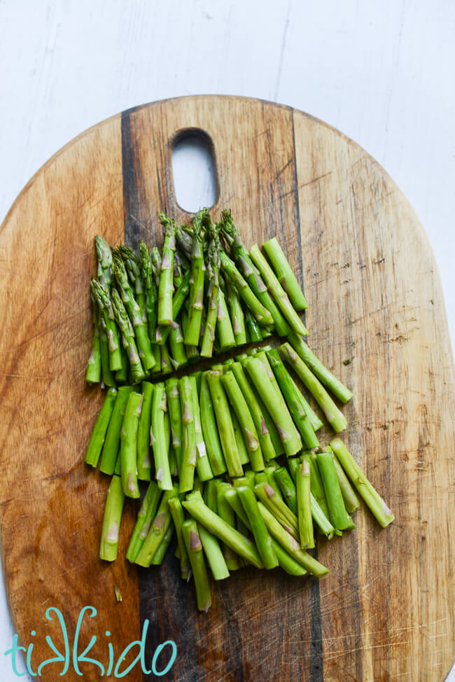 Asparagus cut into bite sized pieces on a cutting board for making Recipe for Asparagus Pasta.