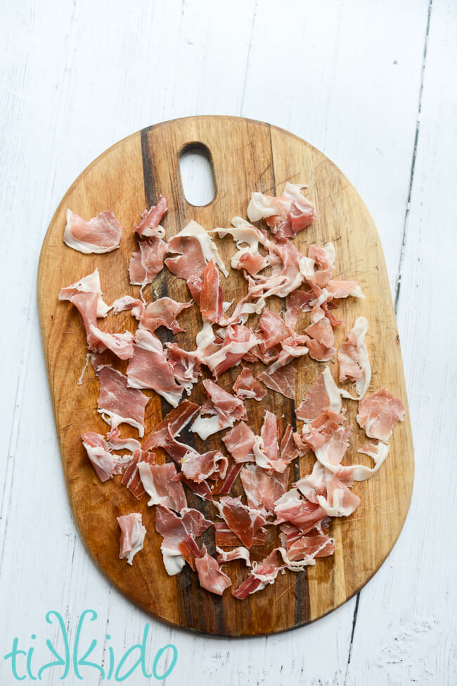 Prosciutto chopped on a wooden cutting board for making prosciutto, asparagus, and mushroom pasta.