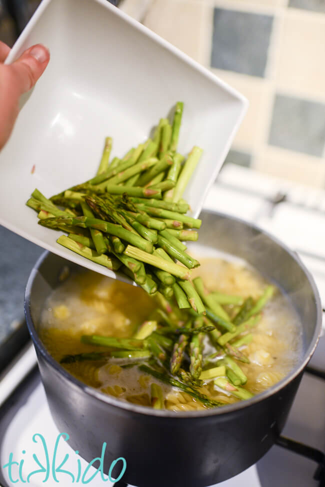 Raw asparagus being added to boiling pasta water for the Recipe for Asparagus Pasta.