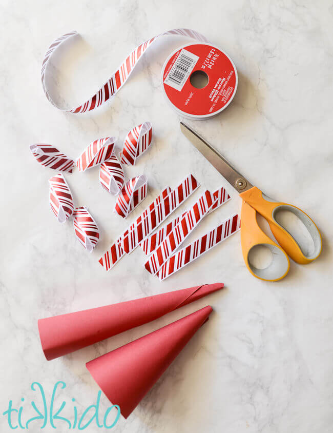 Materials for making peppermint striped Christmas tree mantel decorations out of ribbon and paper.