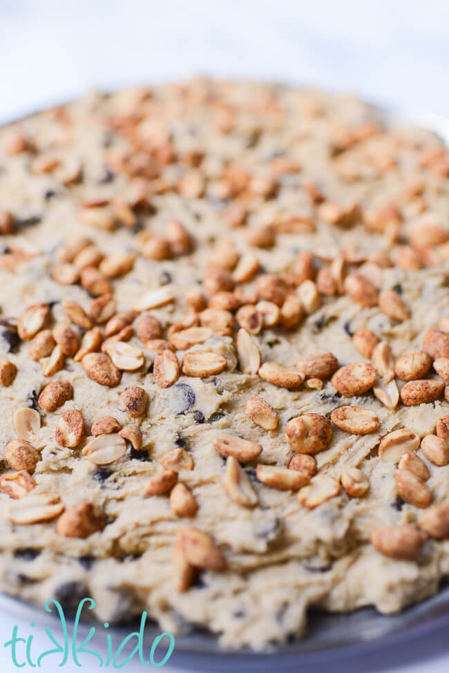 Peanuts pressed into unbaked chocolate chip cookie dough to make a rocky road pizza cookie.