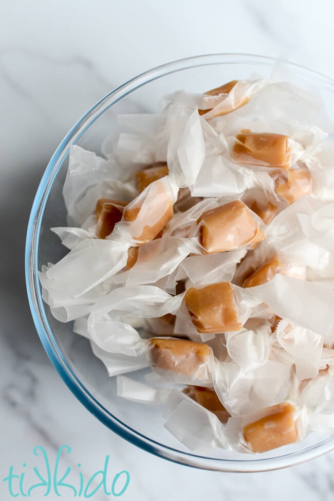 Homemade caramels made with a Salted Caramels recipe in a clear bowl.
